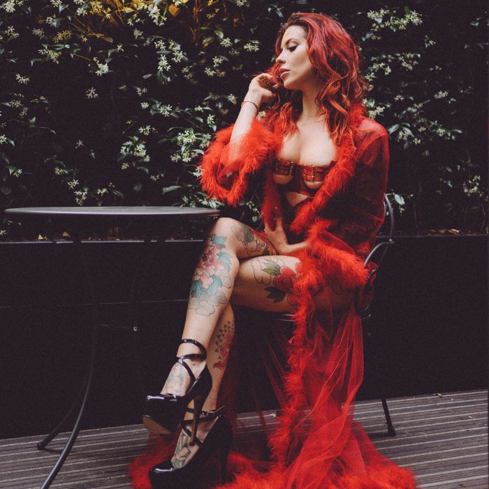 Mistress Adreena in red lingerie with legs crossed
