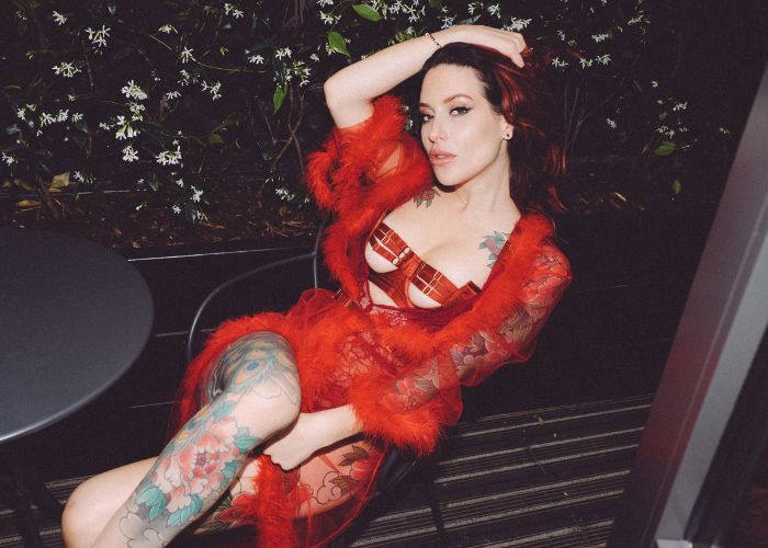 Mistress Adreena in red lingerie reclining in a chair