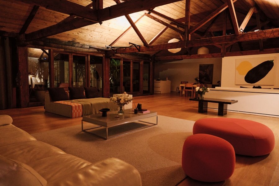 Spacious loft with wooden beams, seating area, coffee table, rug, and modern art on the wall.